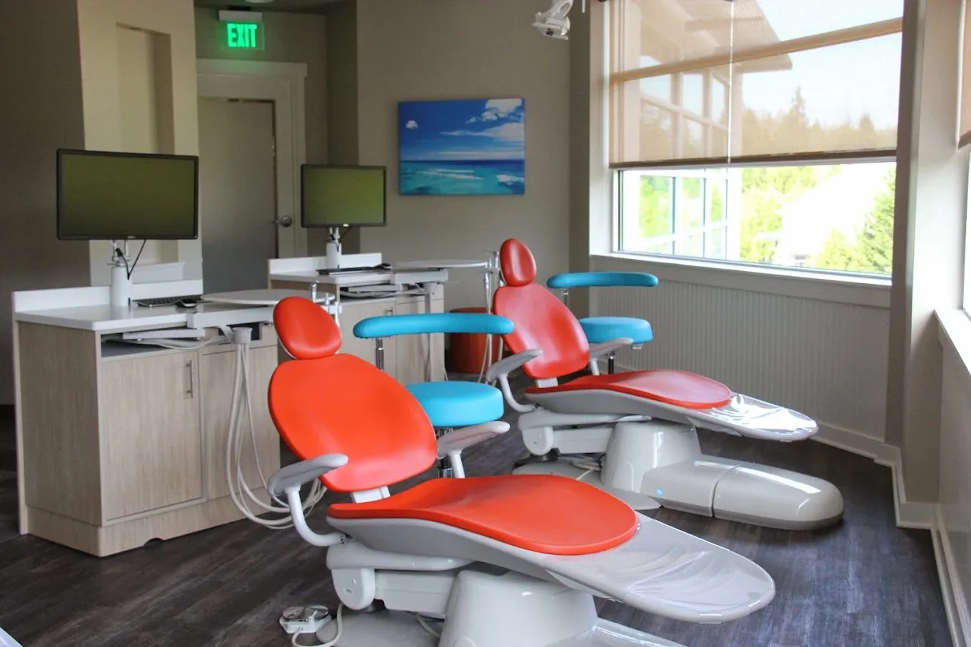 Our sunny treatment area with bright orange and ocean-blue dental chairs